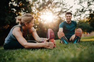 Two people sitting in a field, stretching before exercising